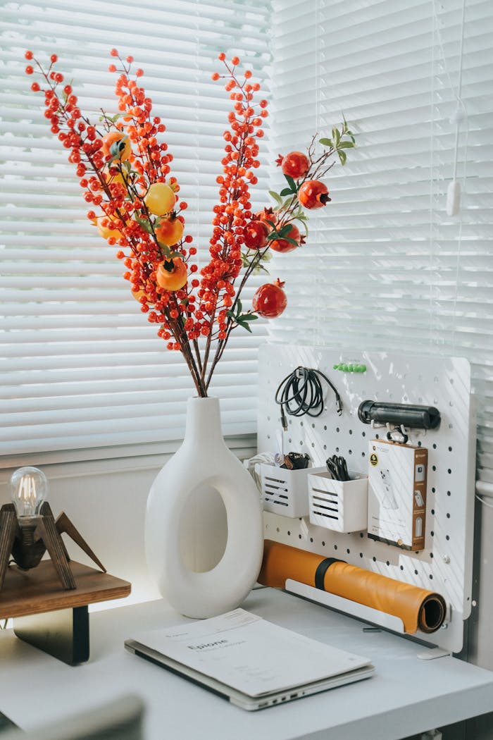 Stylish home office setup with a contemporary vase and vibrant floral decor on a sunny day.